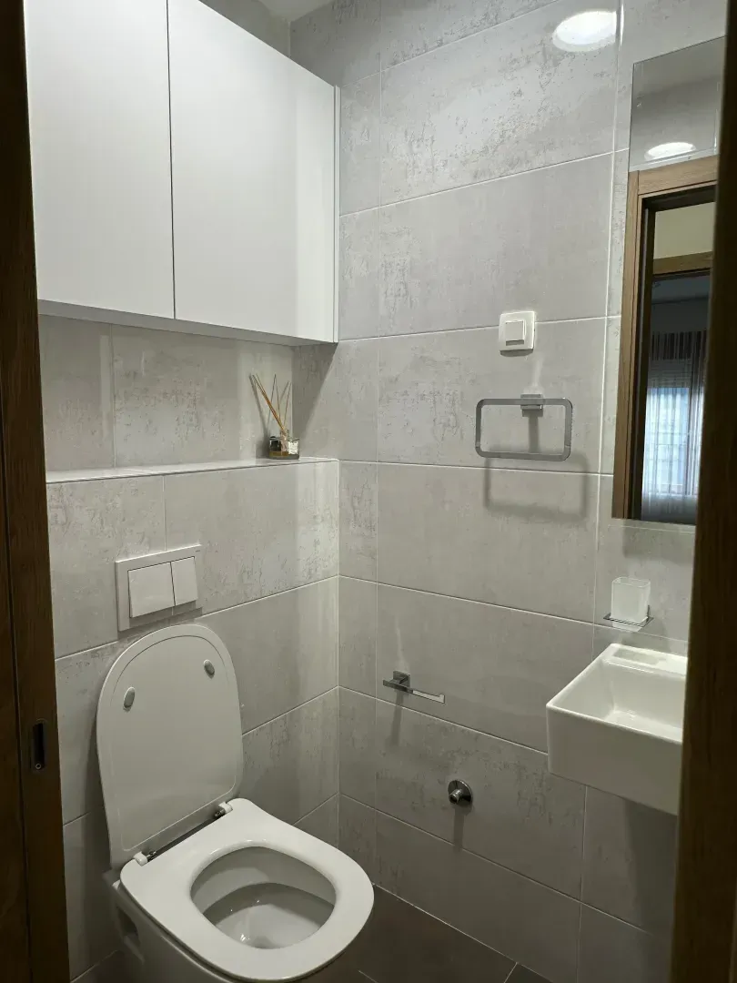 Small bathroom with white sanitary ware and grey wall tiles.