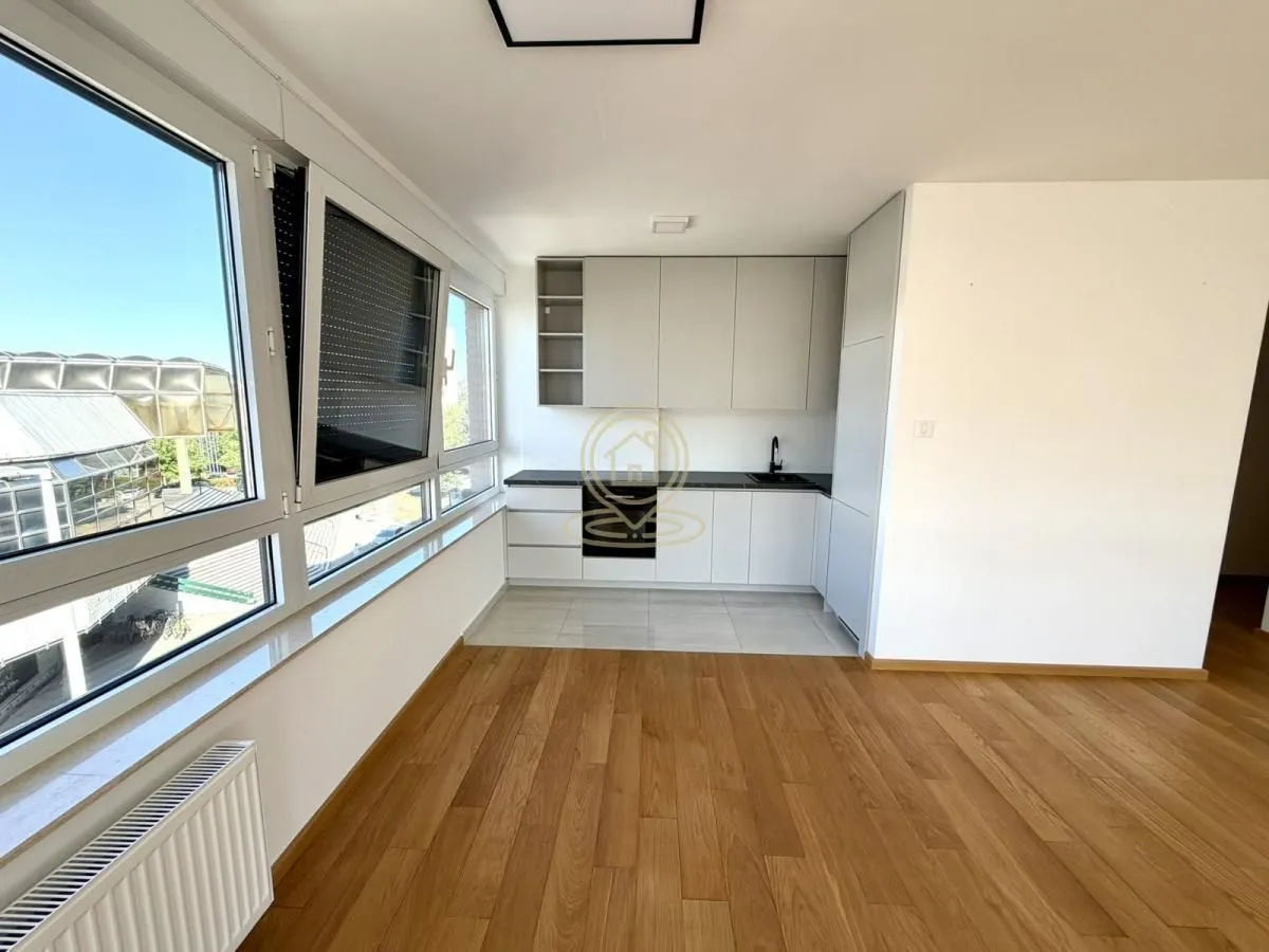 Small modern kitchen with white cabinets and large windows allowing plenty of natural light.