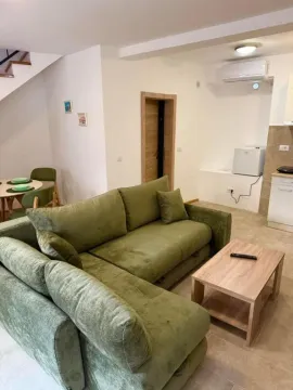 Living room with a green corner sofa and a wooden coffee table. - image 18