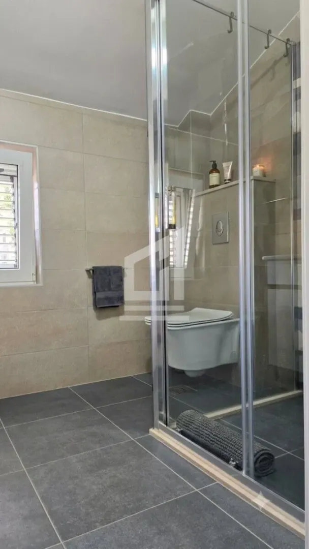 Modern bathroom with a shower cabin and a wall-hung toilet.