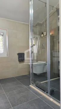 Modern bathroom with a shower cabin and a wall-hung toilet. - image 5