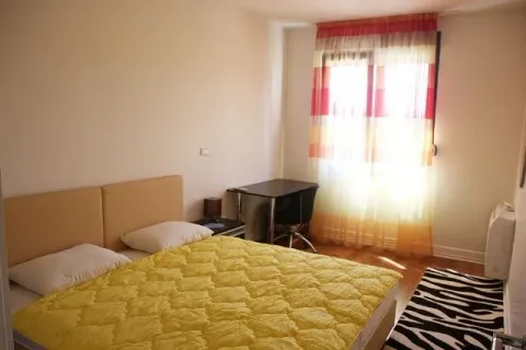 Spavaća soba sa bračnim krevetom, radnim stolom i prozorom sa šarenim zavjesama. - image 4