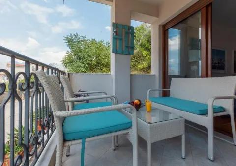 Furnished covered balcony with seating furniture and a green view. - image 6
