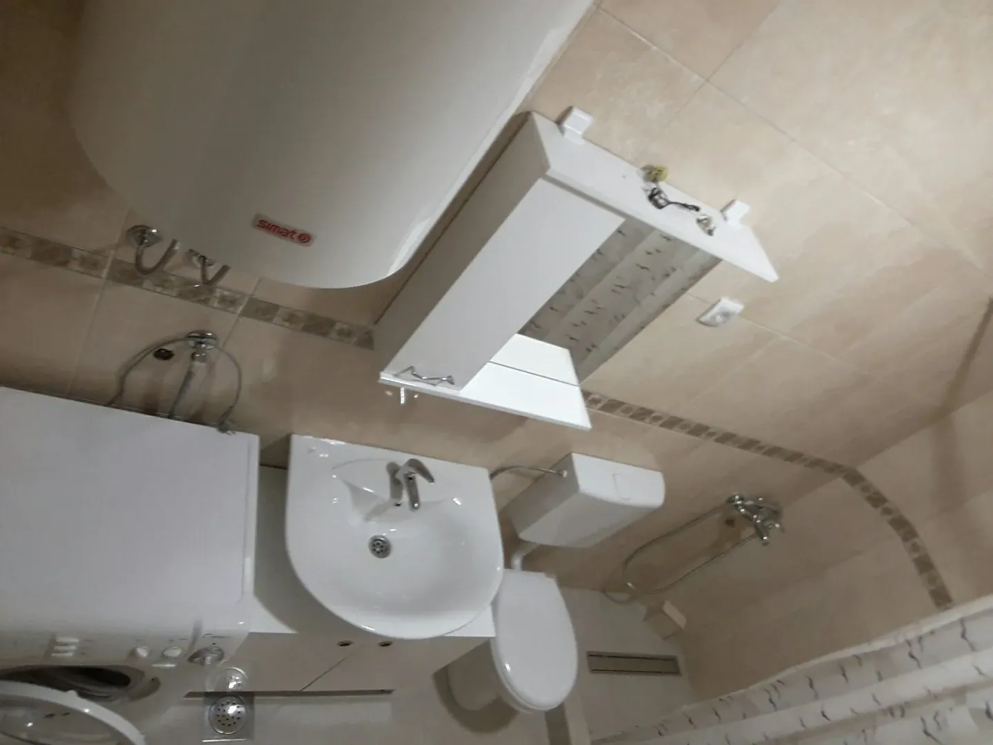 A bathroom with a washing machine, sink, and water heater.