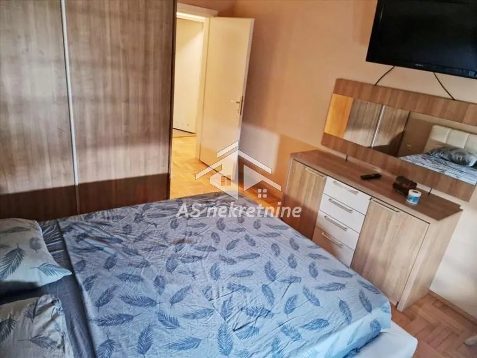 Furnished bedroom with a double bed, wardrobe, and a dresser with a mirror.