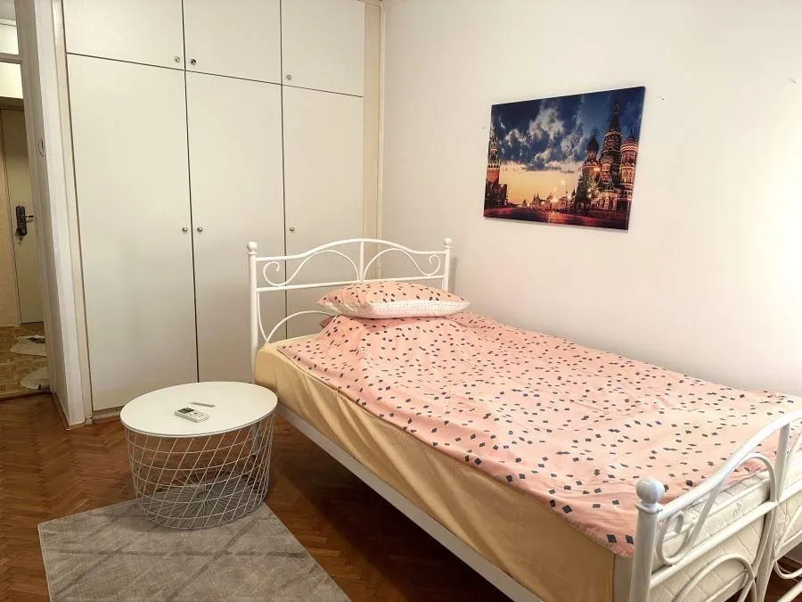 Furnished bedroom with a bed, wardrobe, and a small table.