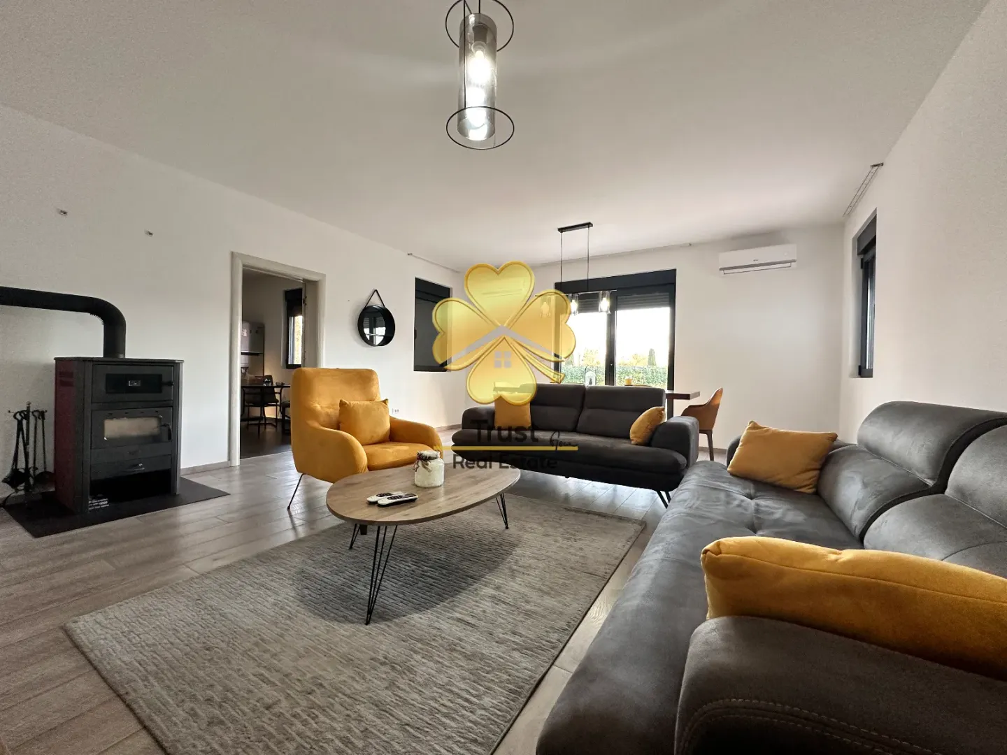Spacious living room with a fireplace, seating set, and dining area in the background.