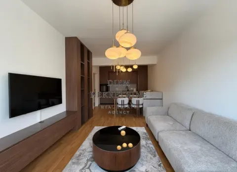 Living room with a sofa, TV, and dining area in the background. - image 5
