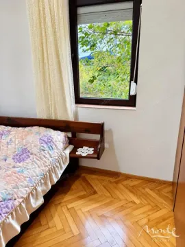 Spavaća soba sa drvenim krevetom i prozorom koji gleda na dvorište. - image 3