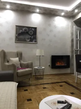 Living room featuring a comfortable armchair and a wall-mounted electric fireplace. - image 12