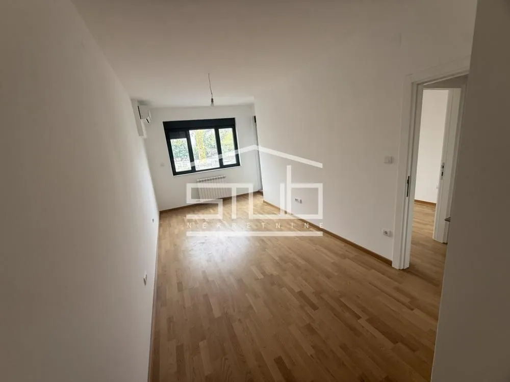Prazna soba sa drvenim podom i belim zidovima.