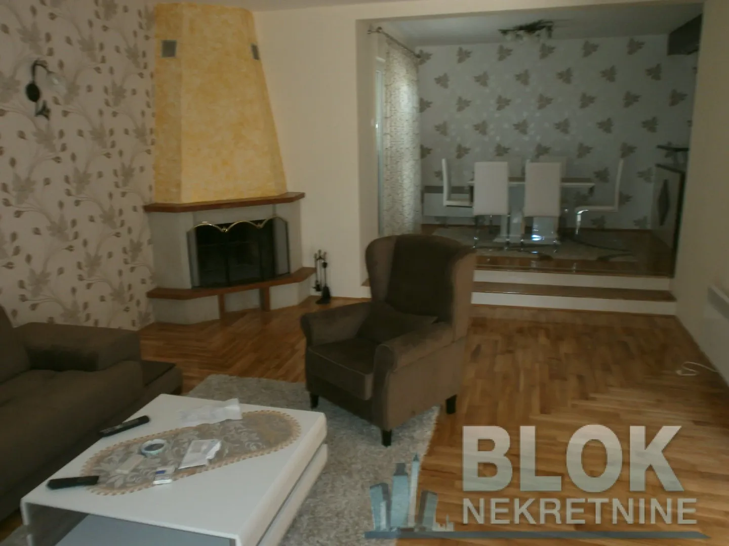 Living room with a sofa set, armchair, fireplace and a view of the dining area.
