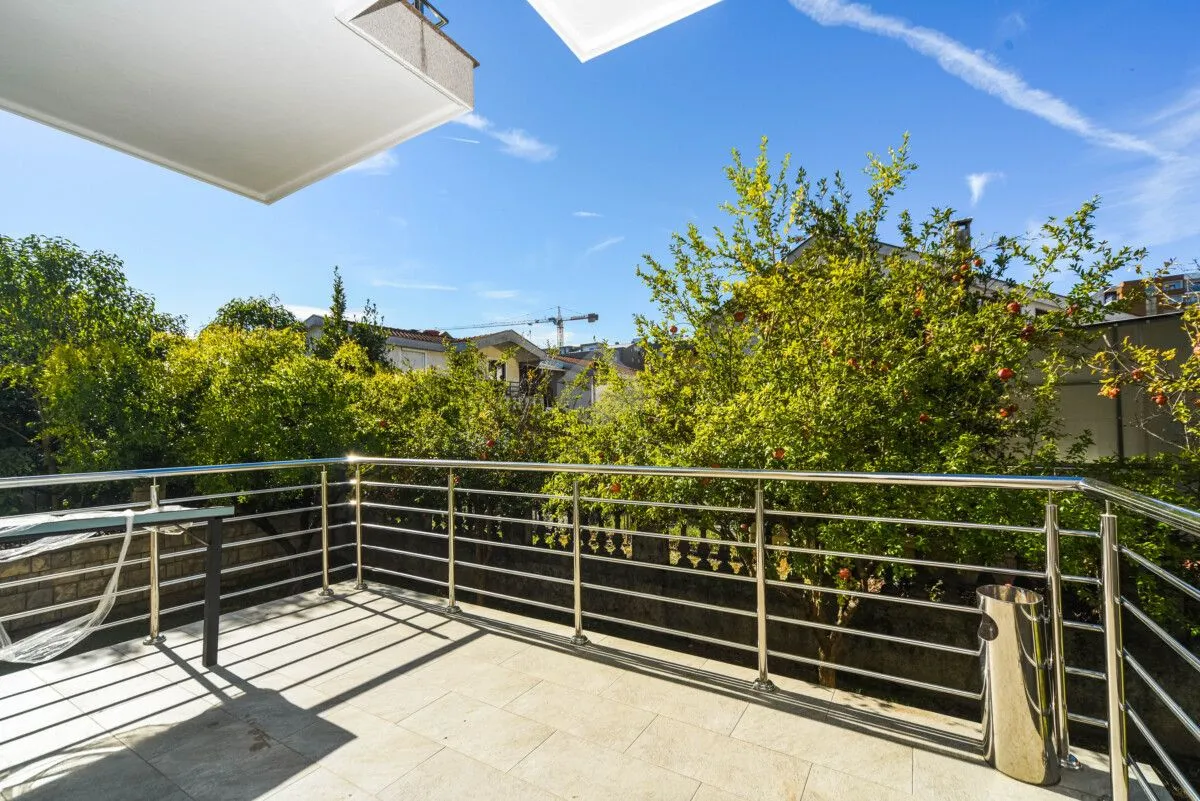 Spacious balcony with metal railing and green surroundings view.