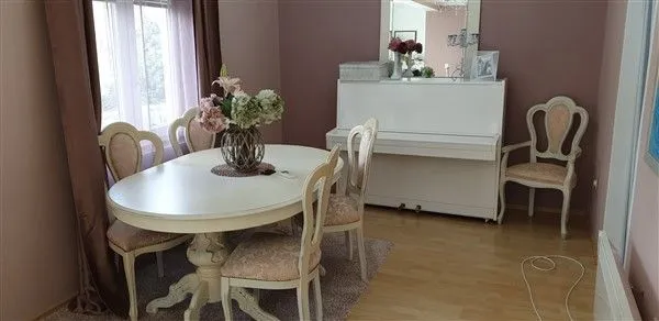 Bright dining area with a white table and a piano.