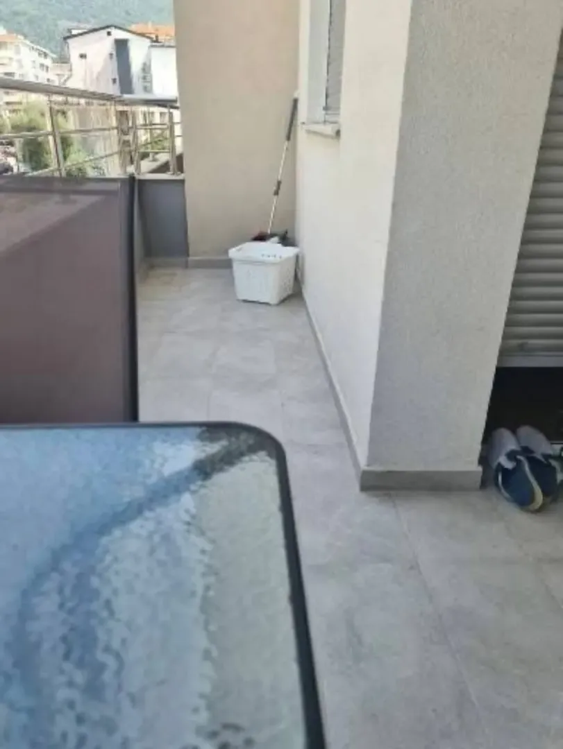 Manji popločani balkon sa ogradom i pogledom na okolne zgrade.