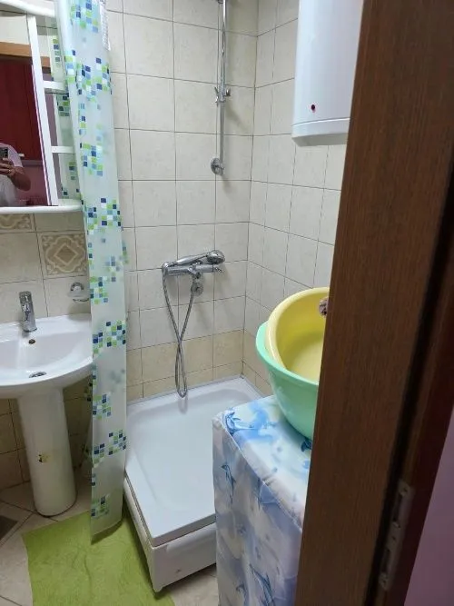 Manje kupatilo sa tuš kabinom, umivaonikom i bojlerom.