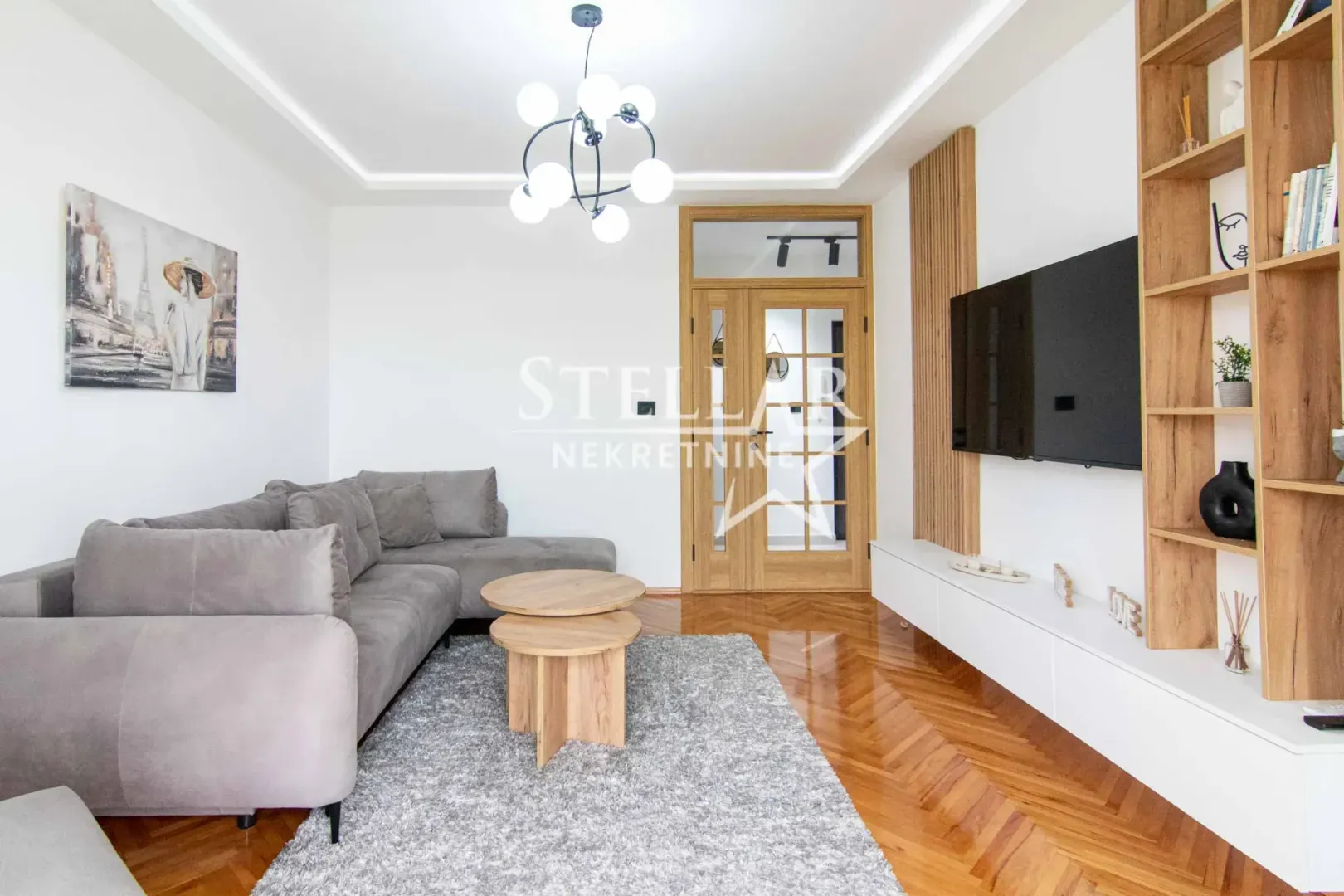 Living room with sofa, TV and wooden shelving units.
