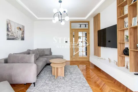 Living room with sofa, TV and wooden shelving units. - image 2