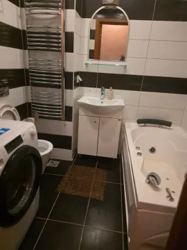 Bathroom equipped with a bathtub, washbasin, toilet, and washing machine. - image 6