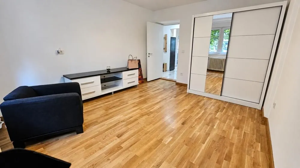 Spavaća soba sa velikim garderoberom, krevetom i parketom na podu.