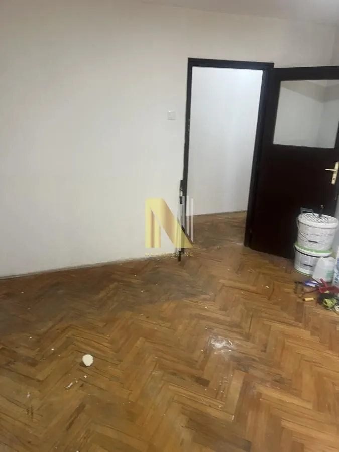 Prazna prostorija sa parketom i vratima u stanu koji se renovira.