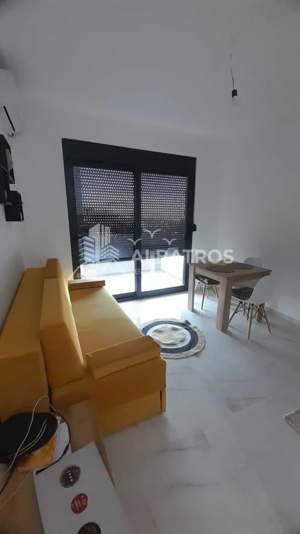 Dnevna soba sa žutom garniturom i trpezarijskim stolom pored balkonskih vrata.