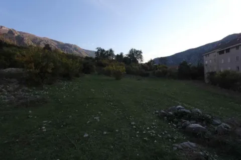 Prostrani zeleni plac okružen brdima i drvećem. - image 6