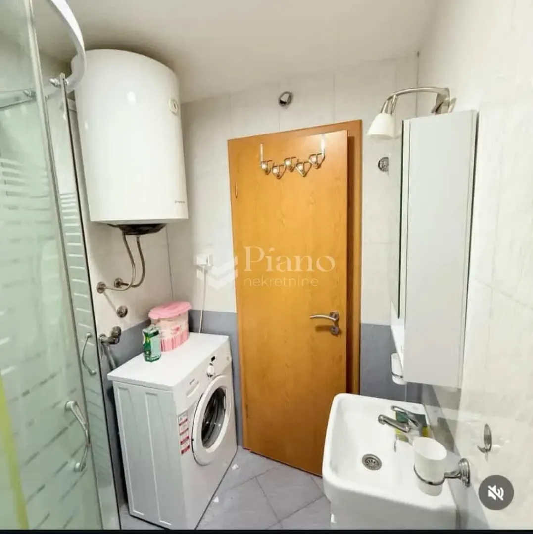 Bathroom equipped with a shower cabin, washbasin, water heater, and washing machine.