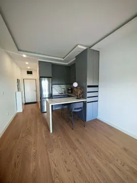 Moderna kuhinja sa šankom i trpezarijskim stolom u svijetlom enterijeru. - image 4