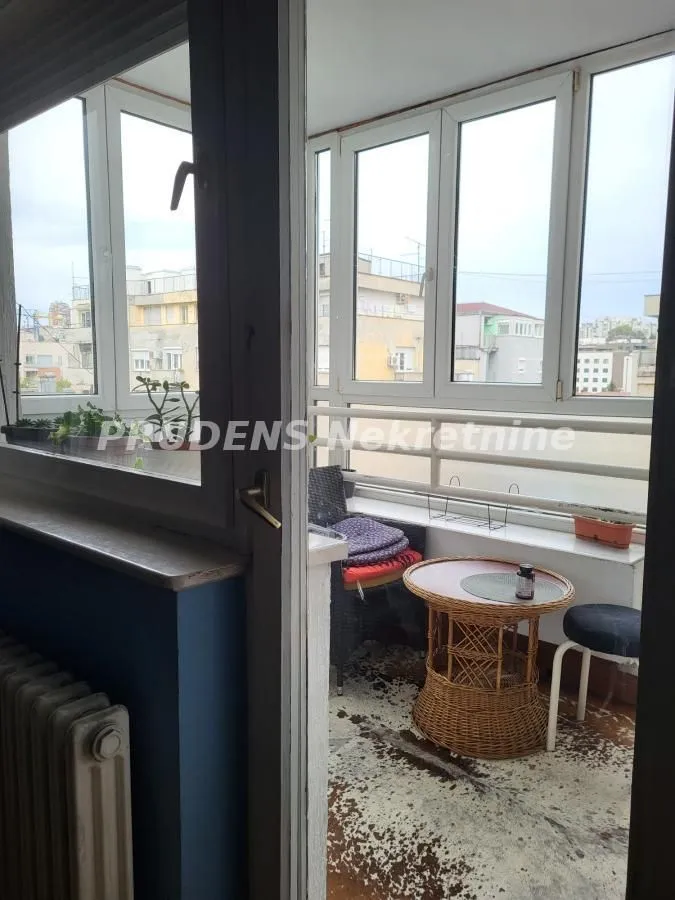 Zastakljeni balkon sa stočićem i stolicama.