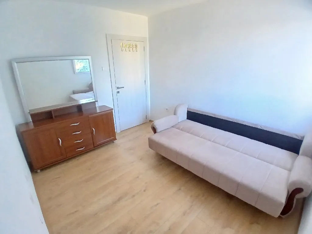 Furnished bedroom with a sofa and a dresser with a mirror.
