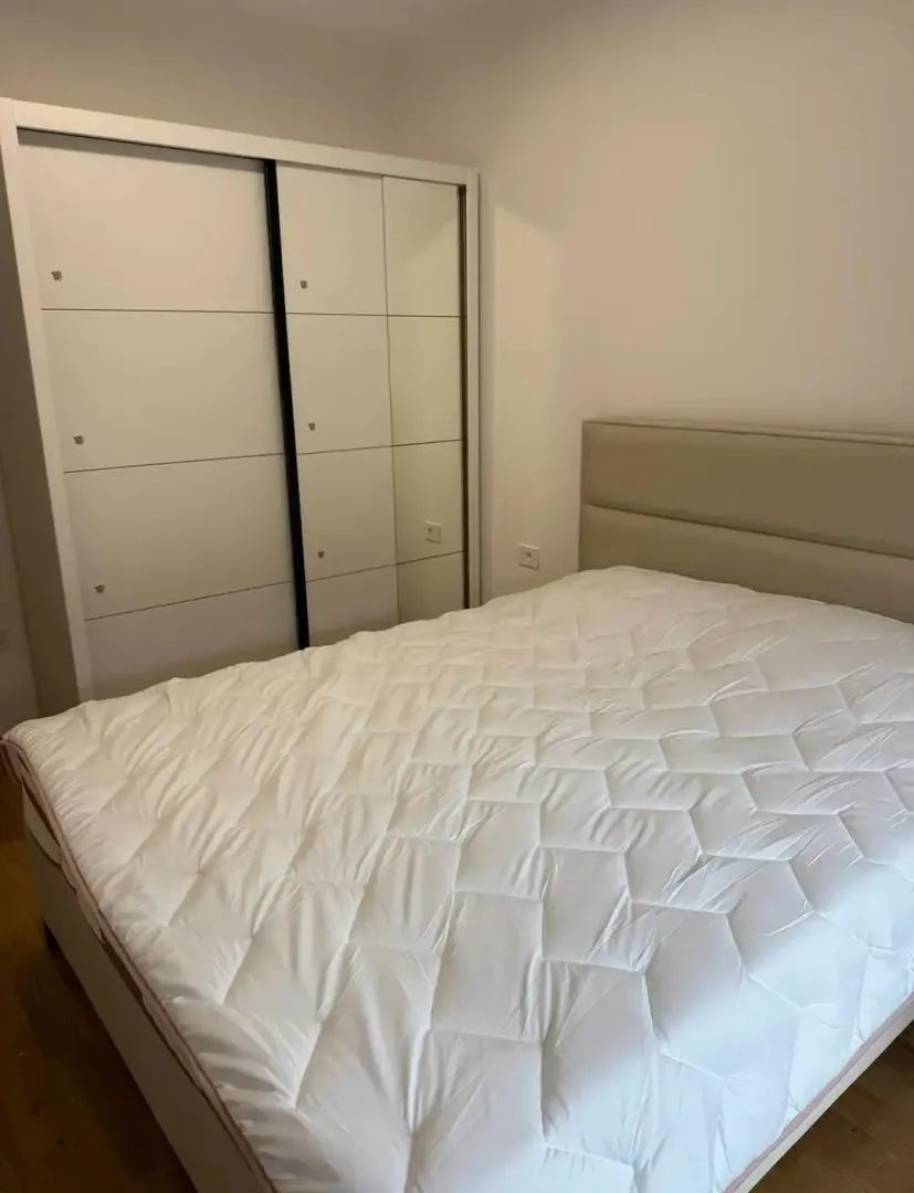 Spavaća soba sa bračnim krevetom i bijelim garderoberom.