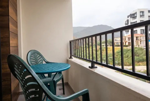 Furnished balcony with seating set and views of nature and surrounding buildings. - image 5