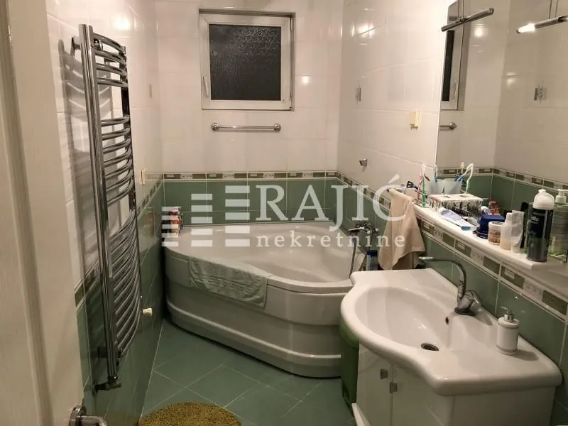 Smaller bathroom with a bathtub, washbasin, and tiles in green and white tones.