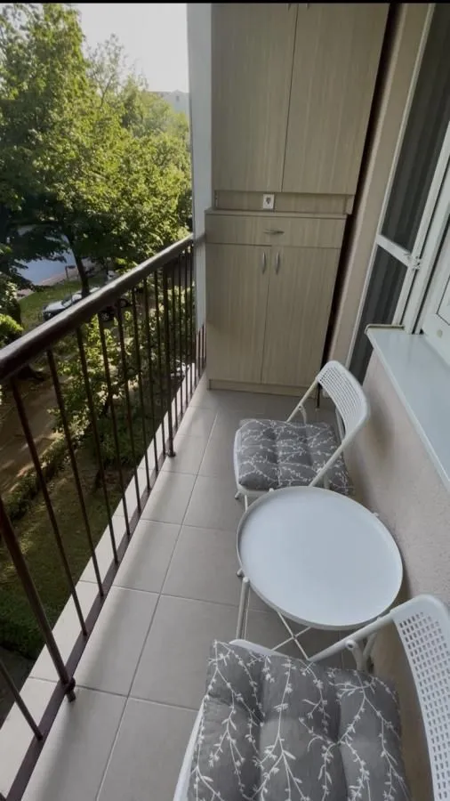 Manji namešten balkon sa stolom, stolicama i ugradnim ormarom.