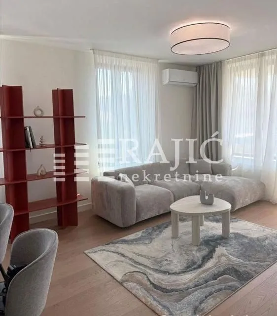 Living room with a sofa, bookshelf, and rug.