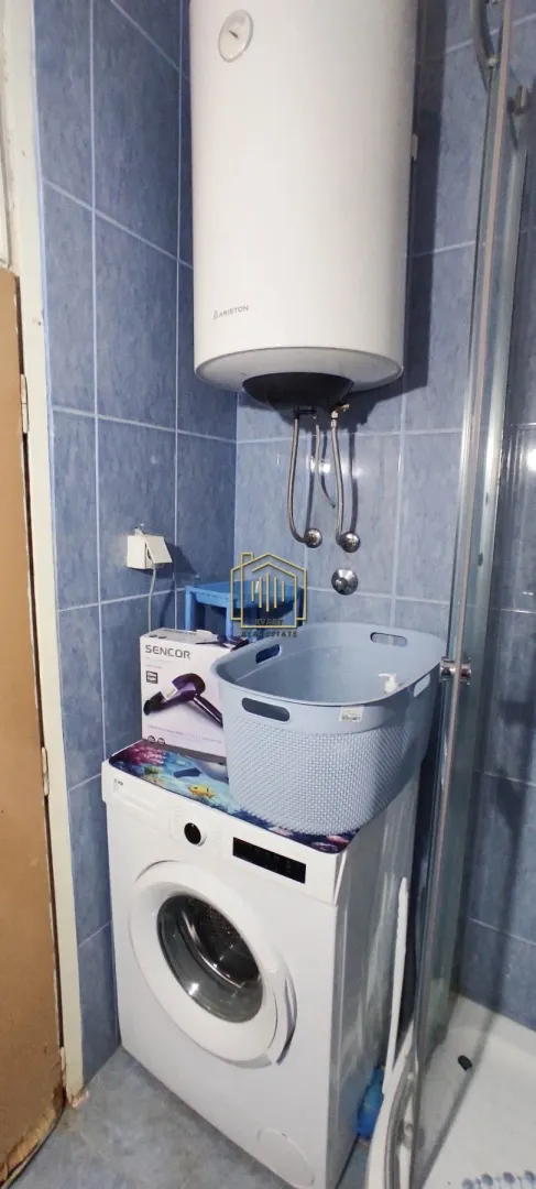 Bathroom with a washing machine, water heater and shower cabin.