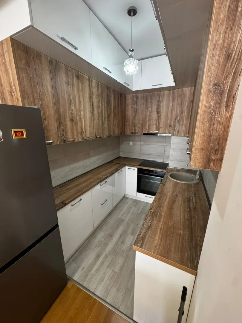 Compact kitchen with wooden cabinetry and built-in appliances.