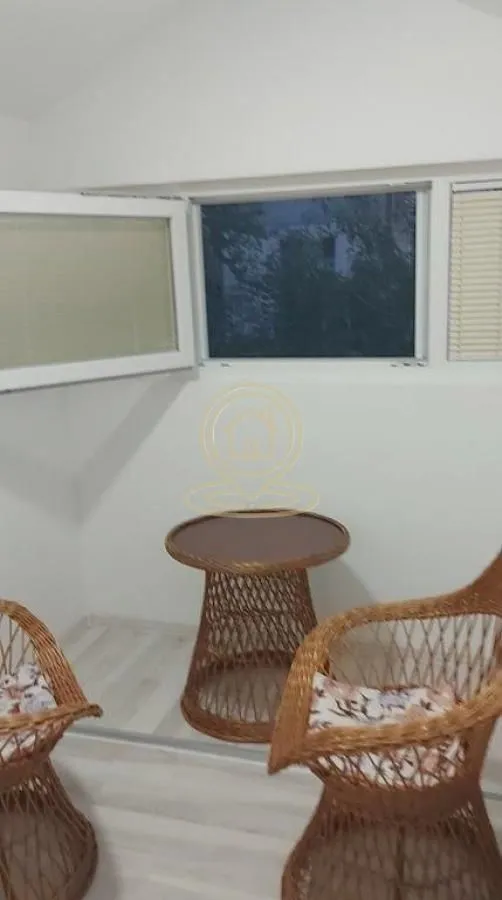 Small enclosed balcony with wicker furniture and windows.