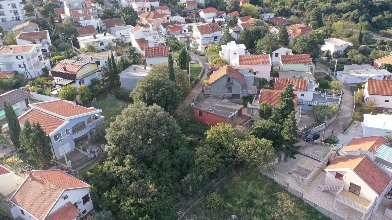Pogled iz vazduha na naselje i okolne kuće sa zelenilom.