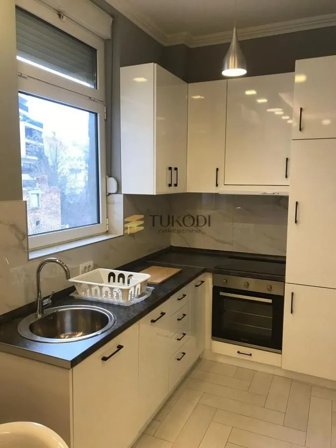 Small bright kitchen with white cabinets and a built-in oven.