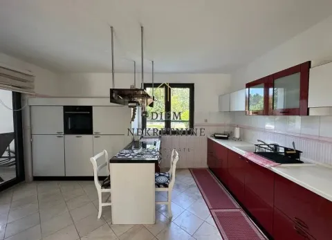 Spacious kitchen with a dining island and red kitchen cabinets. - image 11