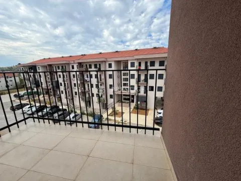 Pogled sa balkona na zgradu i parking sa parkiranim automobilima. - image 13