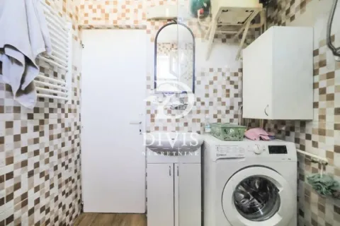 Manje kupatilo sa lavaboom, veš mašinom i pločicama u braon tonovima. - image 13