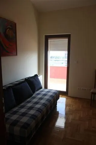Jednostavna soba sa kaučem na razvlačenje i izlazom na balkon.