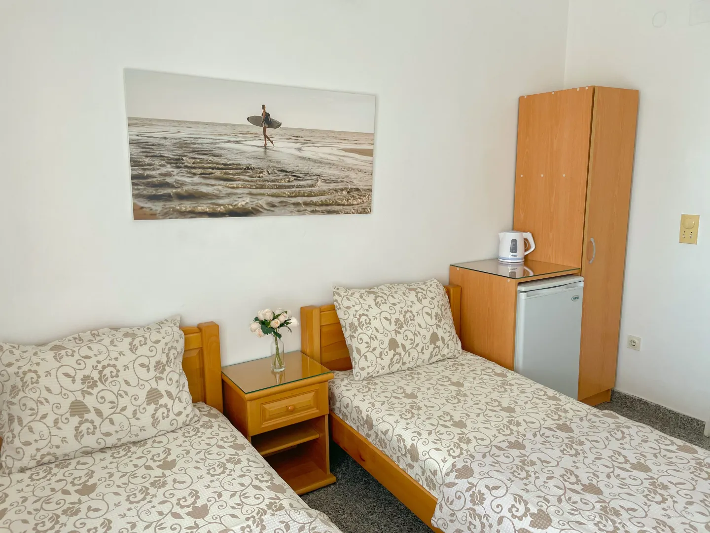 Bedroom with two single beds, a nightstand, and a wooden wardrobe.