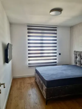 Nameštena spavaća soba sa bračnim krevetom, prozorom i televizorom na zidu. - image 6