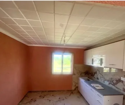 Prazna kuhinja sa bijelim elementima i narandžastim zidovima. - image 4
