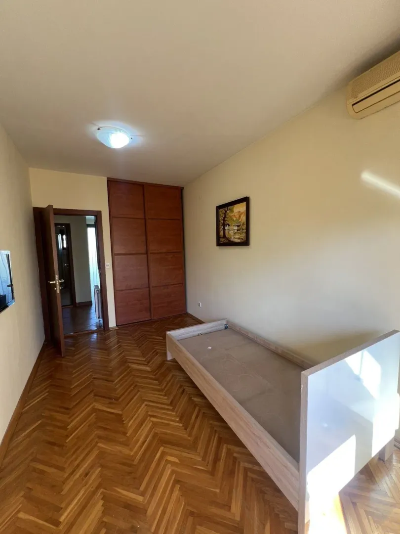 Bright bedroom with parquet flooring, a single bed frame, and a built-in wardrobe.