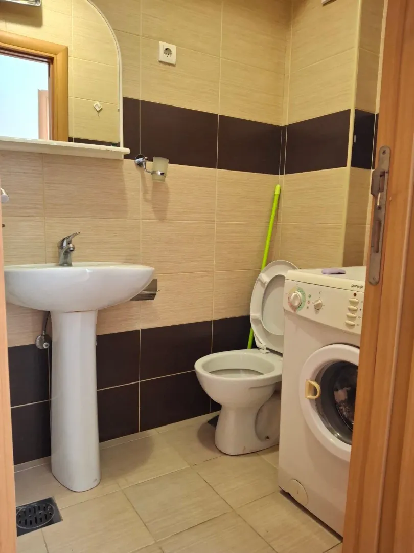 Manje kupatilo sa umivaonikom, WC šoljom i veš mašinom.